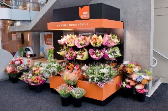 Kiosque orange et noir de Frans Flowers rempli de bouquets colorés et d’arrangements de fleurs en pot.